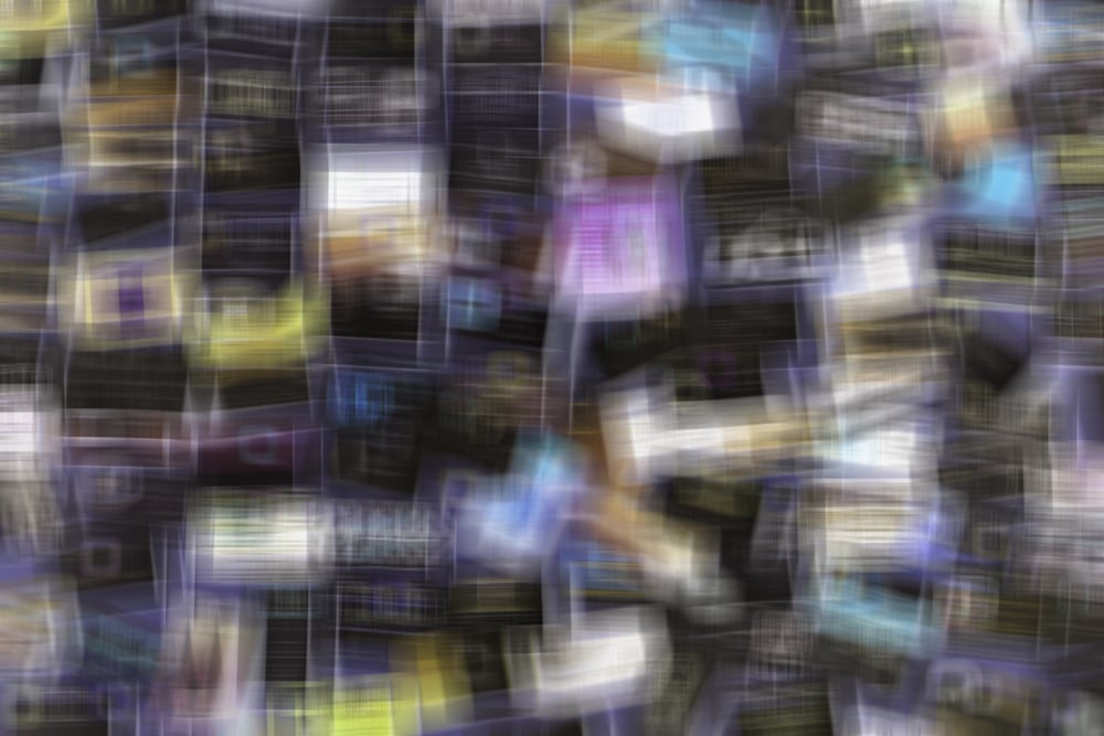 Multicolored abstract of many business cards on a bulletin board, with considerable shape blur, for implied themes of information overload and confusion (one of a series)