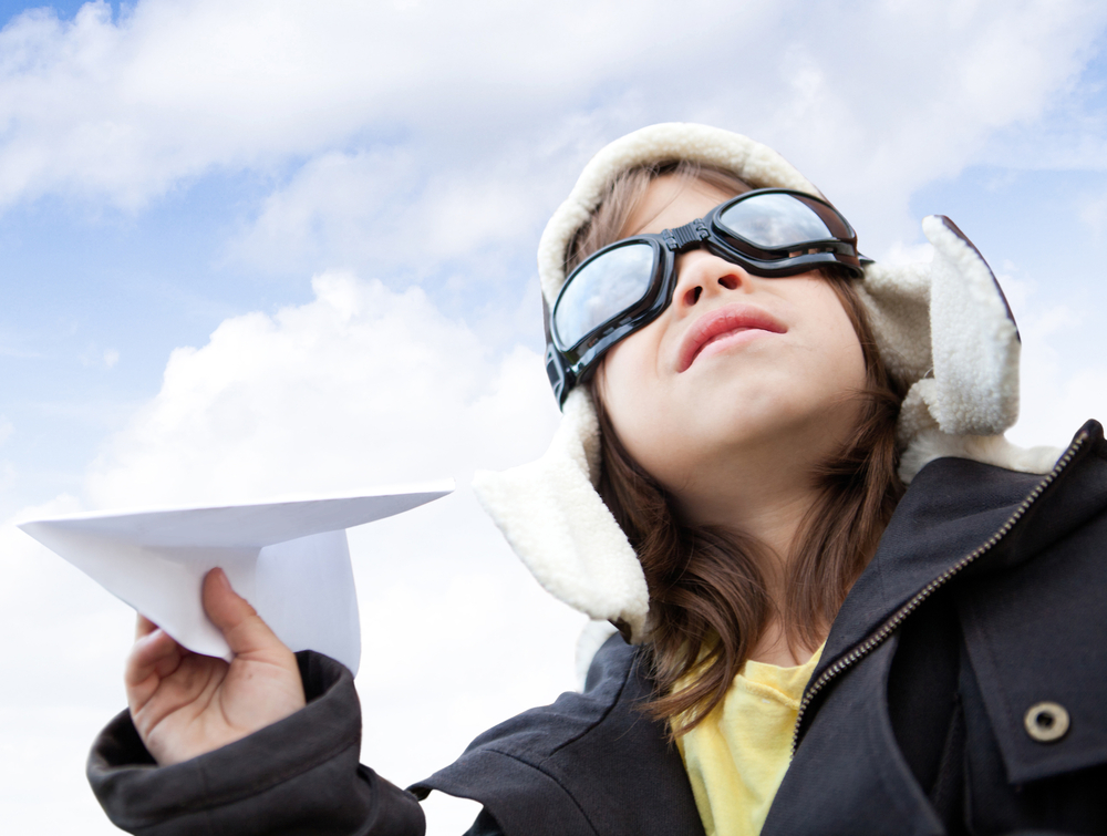 Young boy pilot holding a paper airplane looking at the sky-1